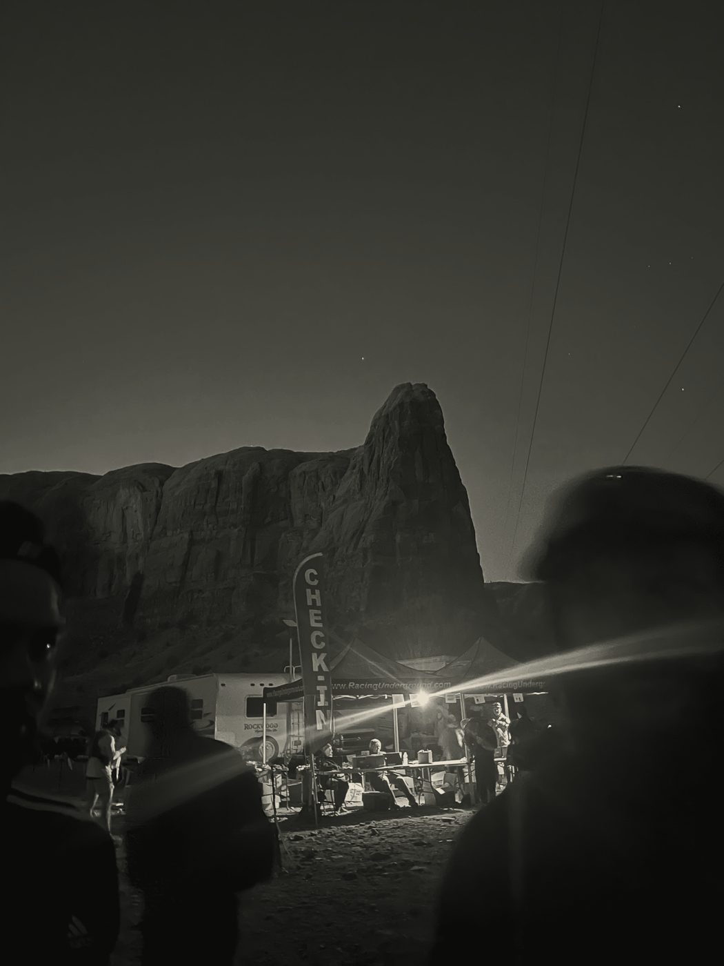 Base camp lit at dusk beneath a rock face
